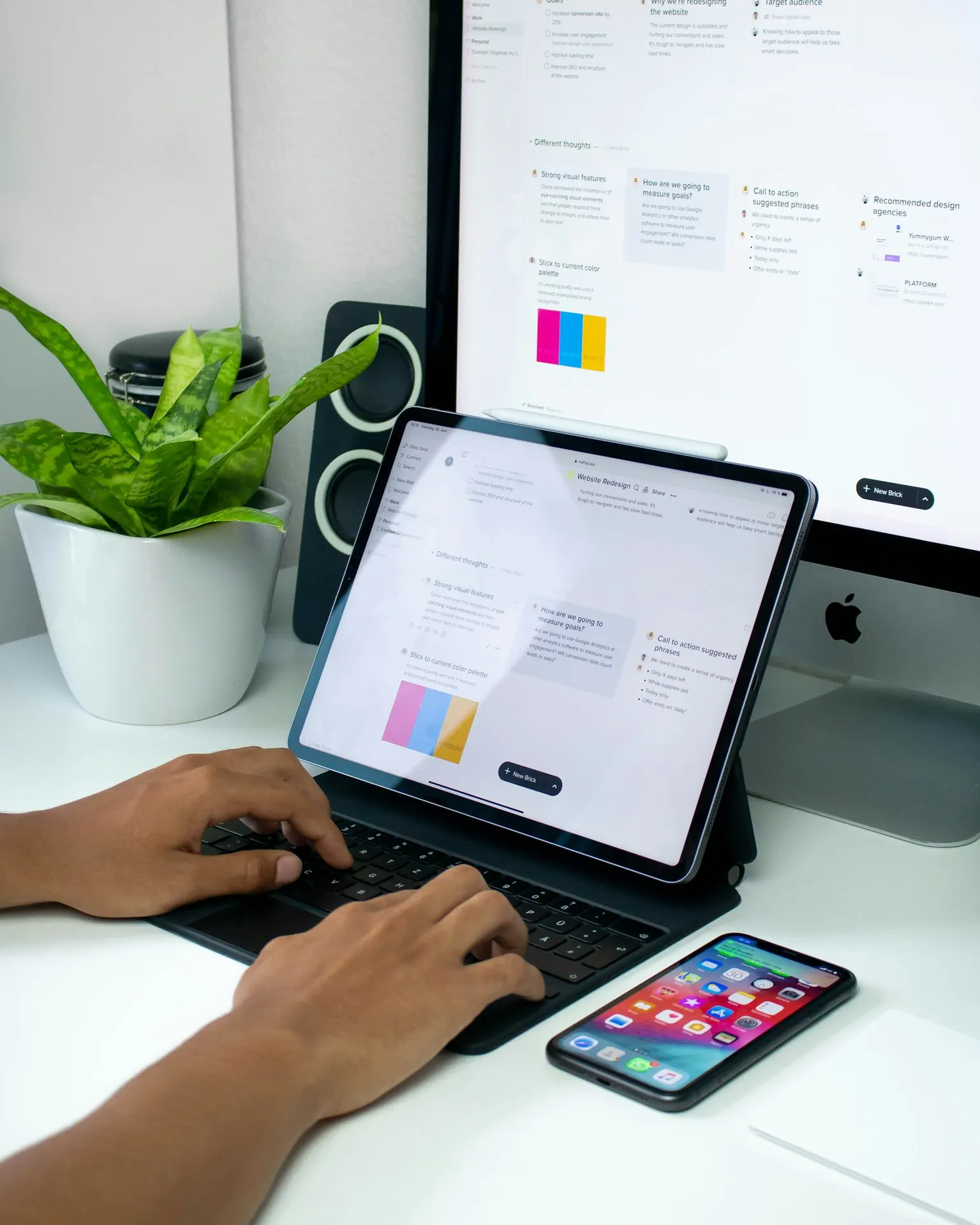 A person working on a website redesign across a monitor and tablet